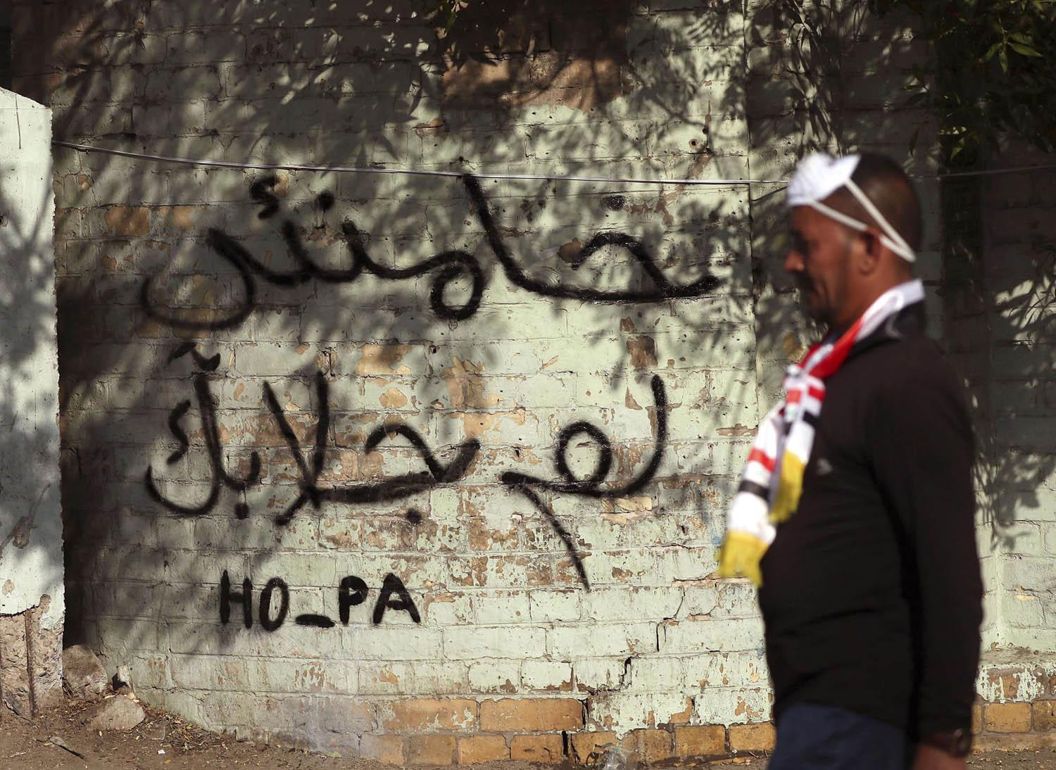 متظاهر عراقي يمر بالقرب من شعارات تنتقد خامنئي في بغداد