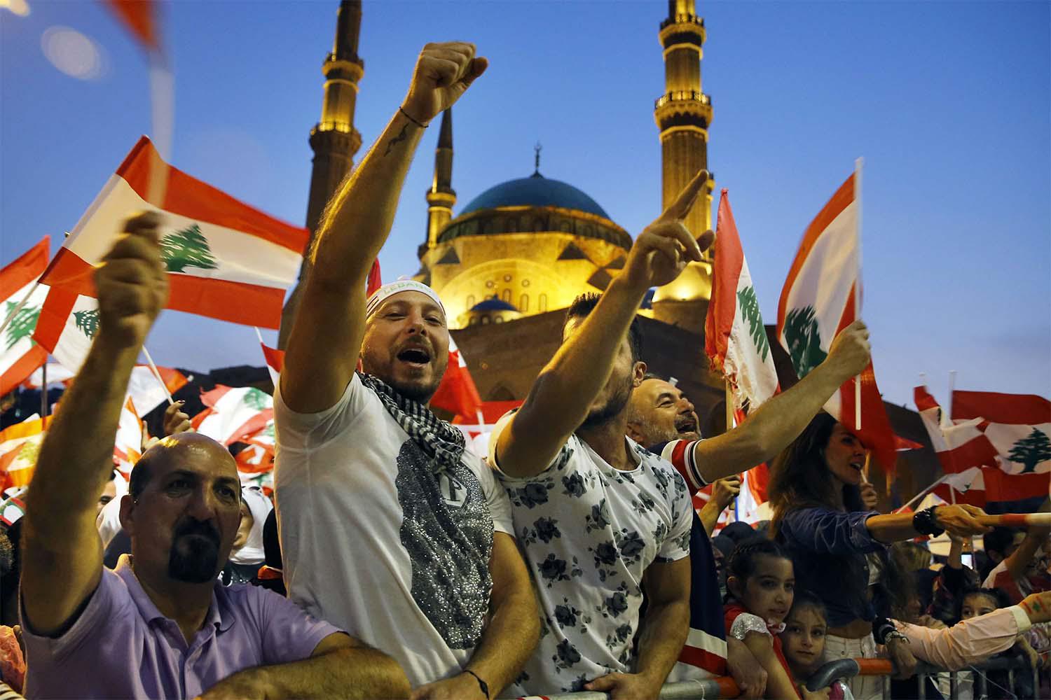 Anti-government protesters wave Lebanese flags and chant slogans, during ongoing demonstrations, in Beirut