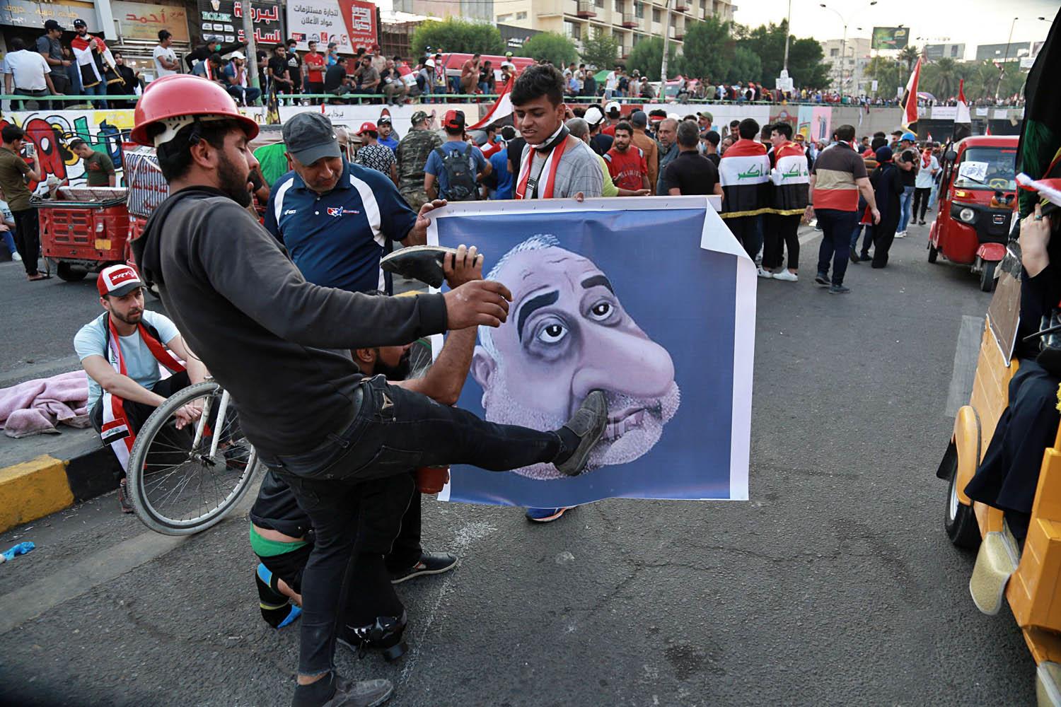 عراقيون يركلون تخطيطا لرئيس الوزراء العراقي عادل عبدالمهدي وسط بغداد
