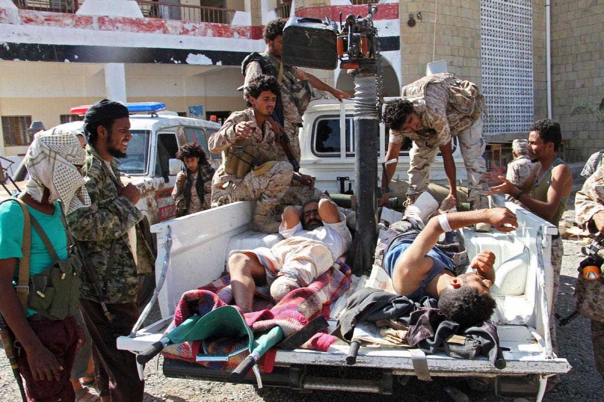 Fighters loyal to the Saudi-backed Yemeni president carry injured men onto the back of a pick-up truck in the western Yemeni coastal town of Mokha
