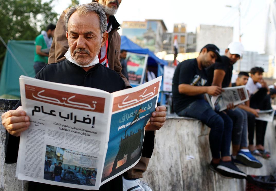An Iraqi demonstrator reads Tuktuk newspaper during the ongoing anti-government protests in Baghdad
