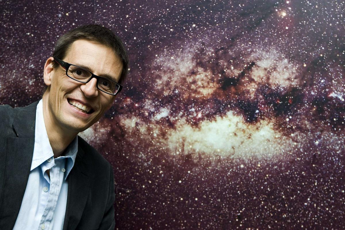 العالم السويسري ديدييه كويلو يقف أمام صورة لمجرة درب التبانة