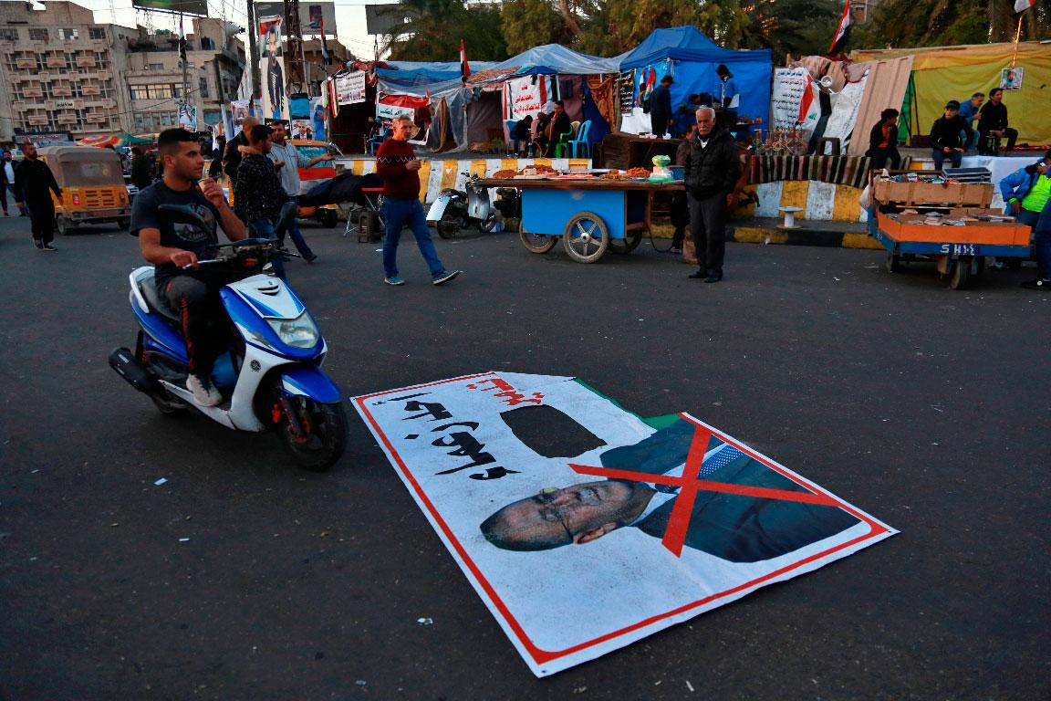 A poster with a defaced photo of Qusay al-Suhail with  Arabic that reads, "one of the leaders of the destruction," seen in Tahrir Square, Baghdad