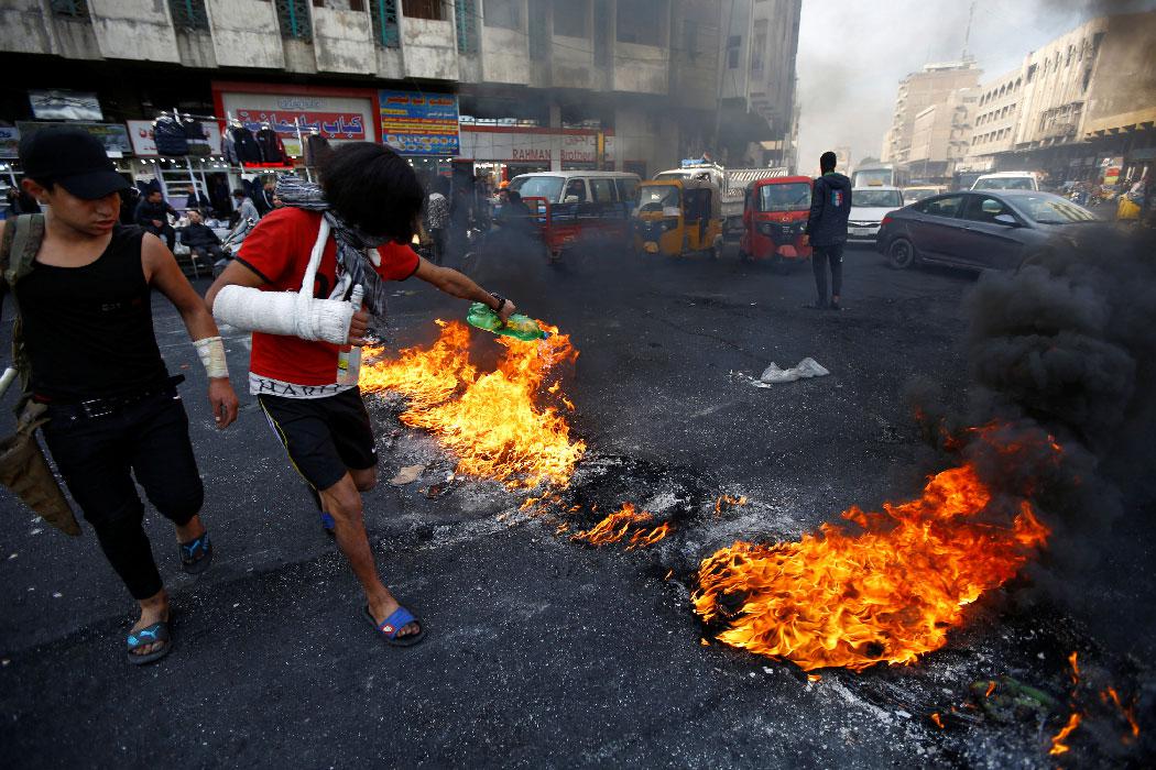 An Iraqi demonstrator sets tires on fire during ongoing anti-government protests in Baghdad