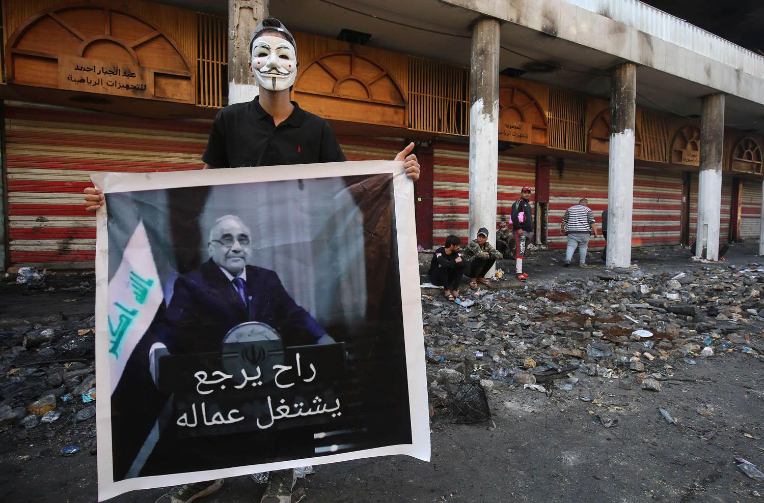 متظاهر يرفع صورة تسخر من رئيس الوزراء العراقي المستقيل عادل عبدالمهدي