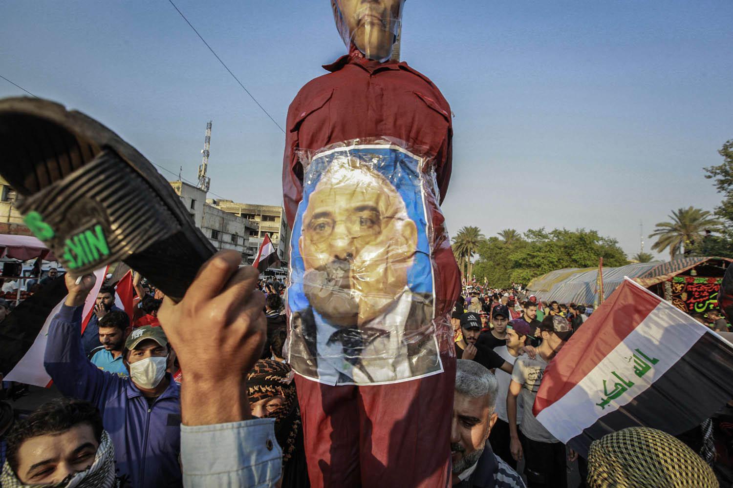 عراقيون يضربون صورة لرئيس الوزراء العراقي عادل عبدالمهدي
