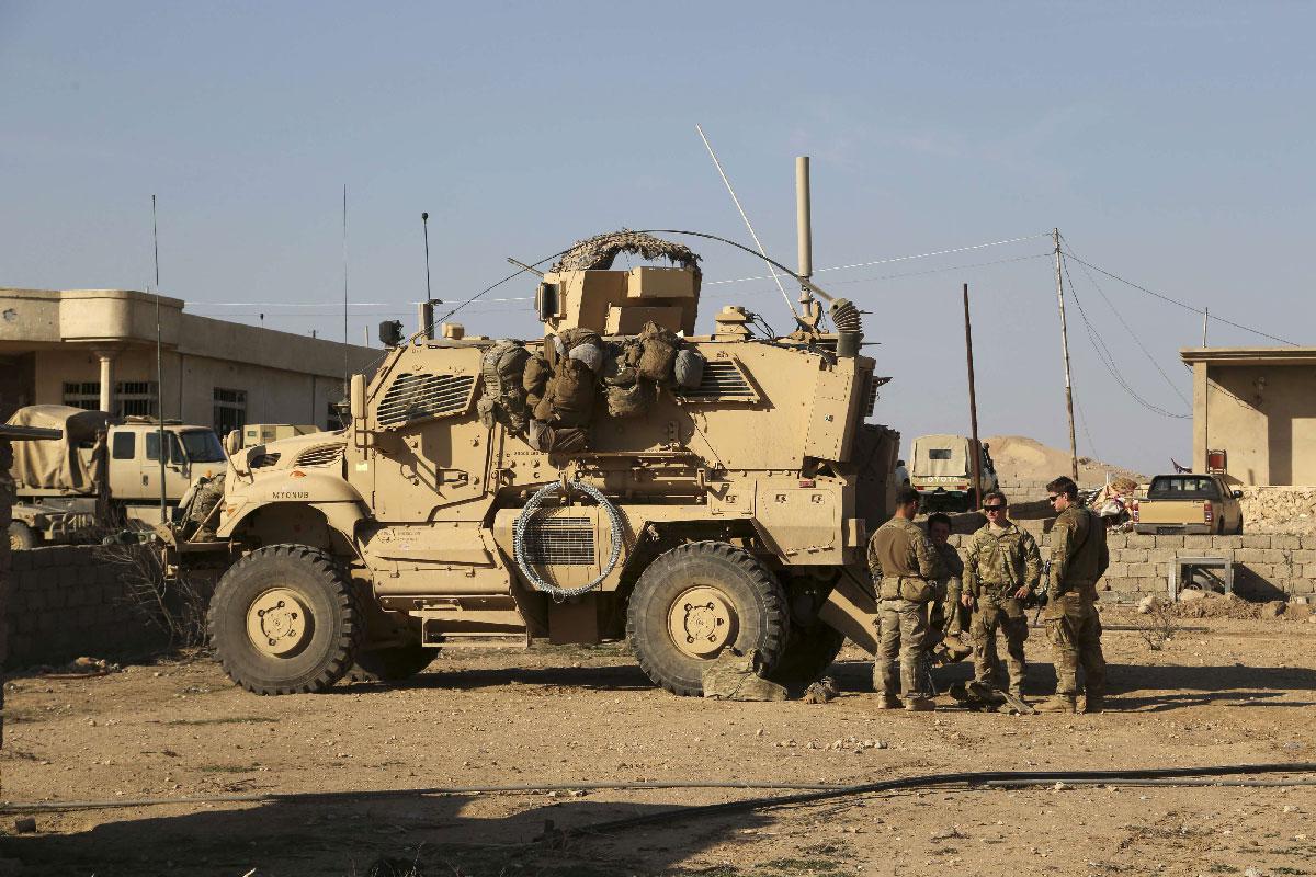 US Army soldiers stand outside their armored vehicle at a joint base in Iraq