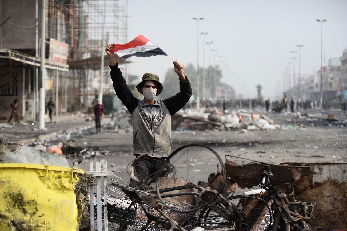 An Iraqi demonstrator carries the national flag in the southern Iraqi Shiite holy city of Najaf