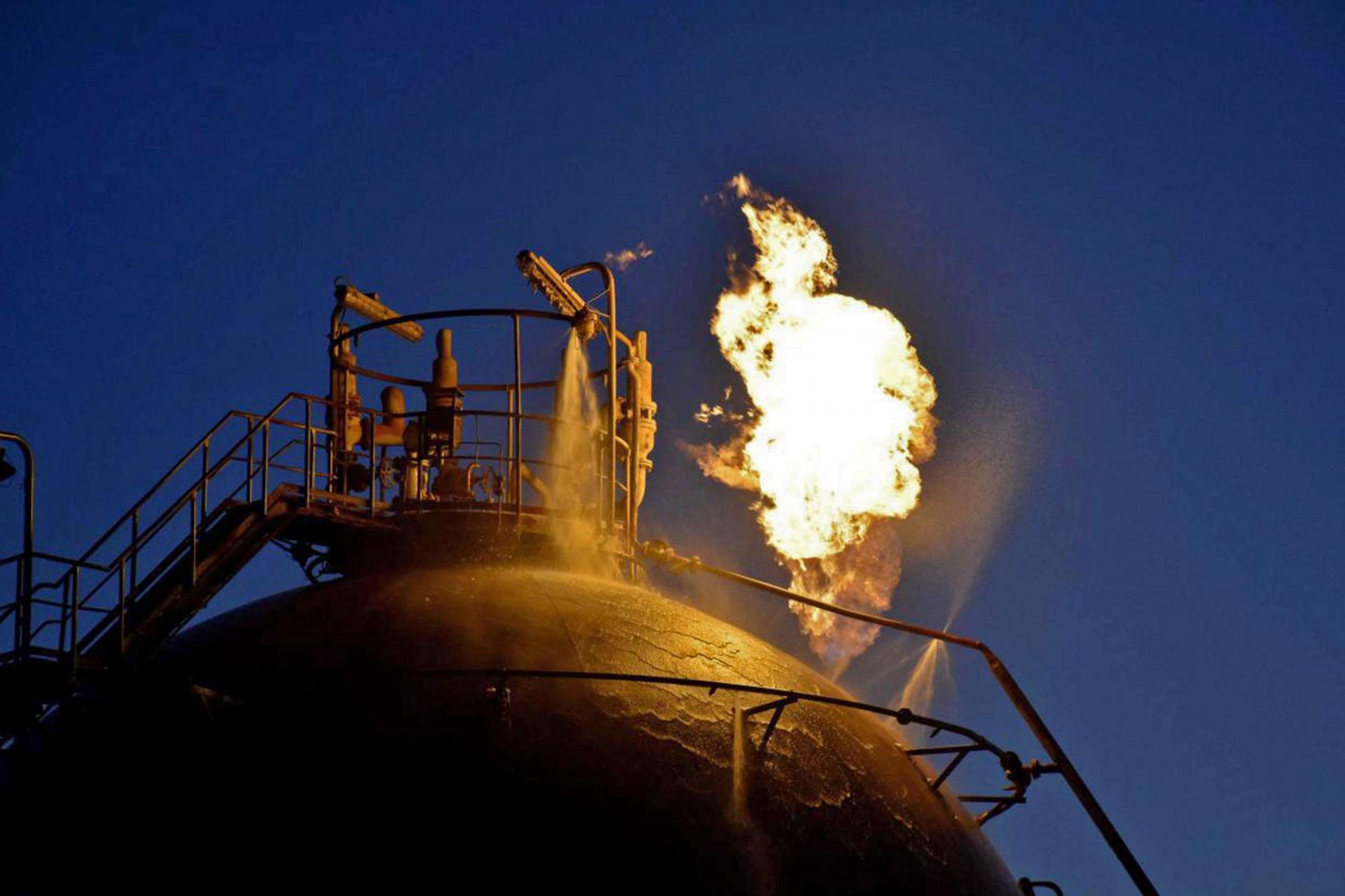 Flame erupting from an oil tank following an attack on Syria's Homs Refinery