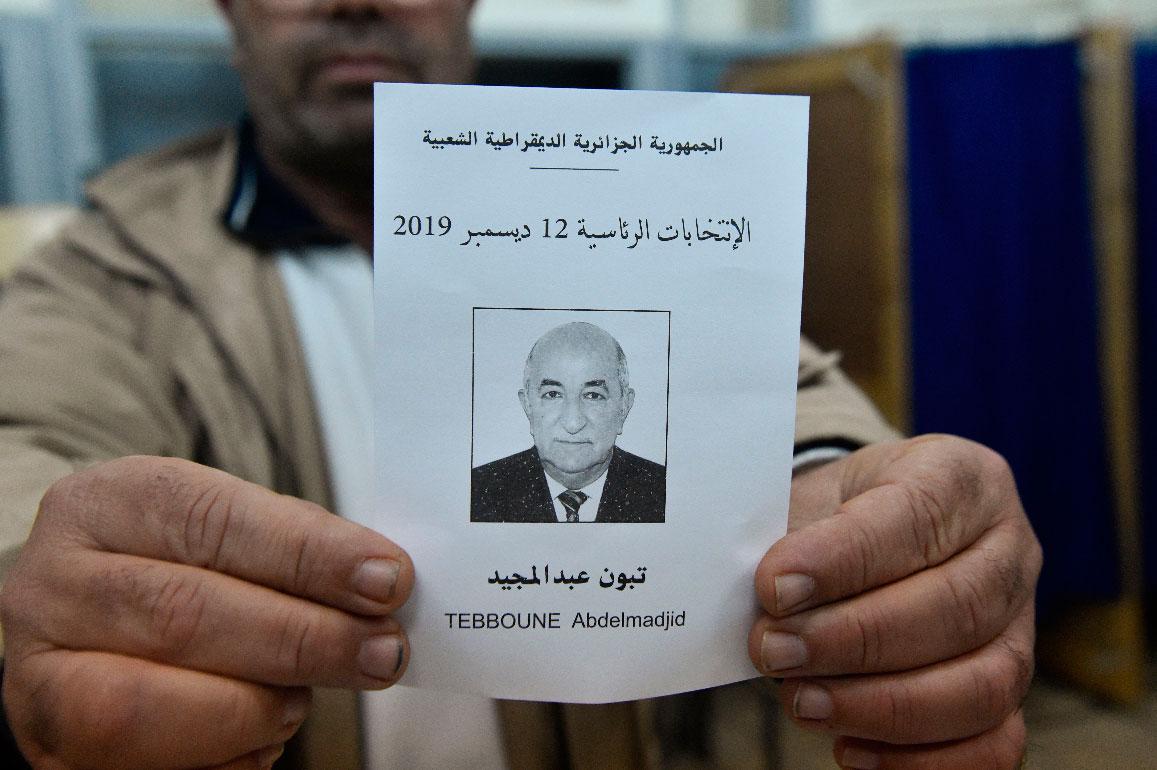 An election official displays a ballot paper of Algeria's presidential candidate Abdelmadjid Tebboune