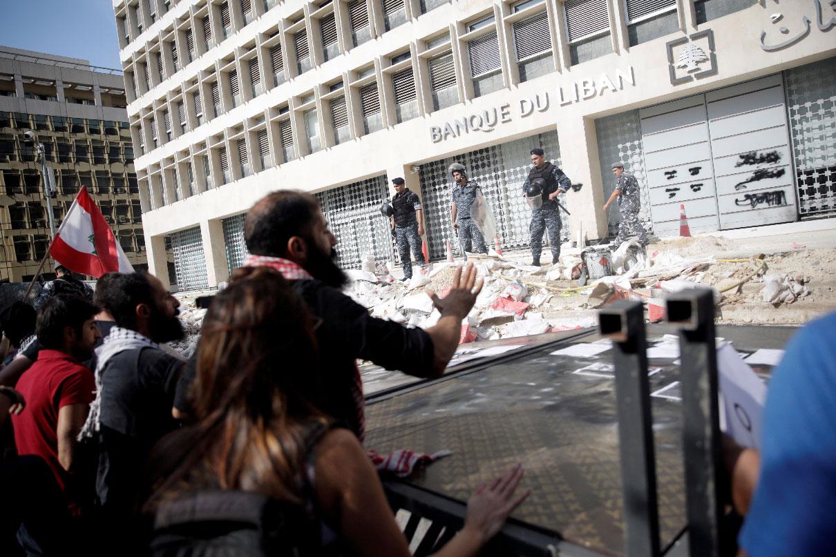 Police officers stand guard as protesters knocked down the fencing as they demonstrate outside of Lebanon Central Bank