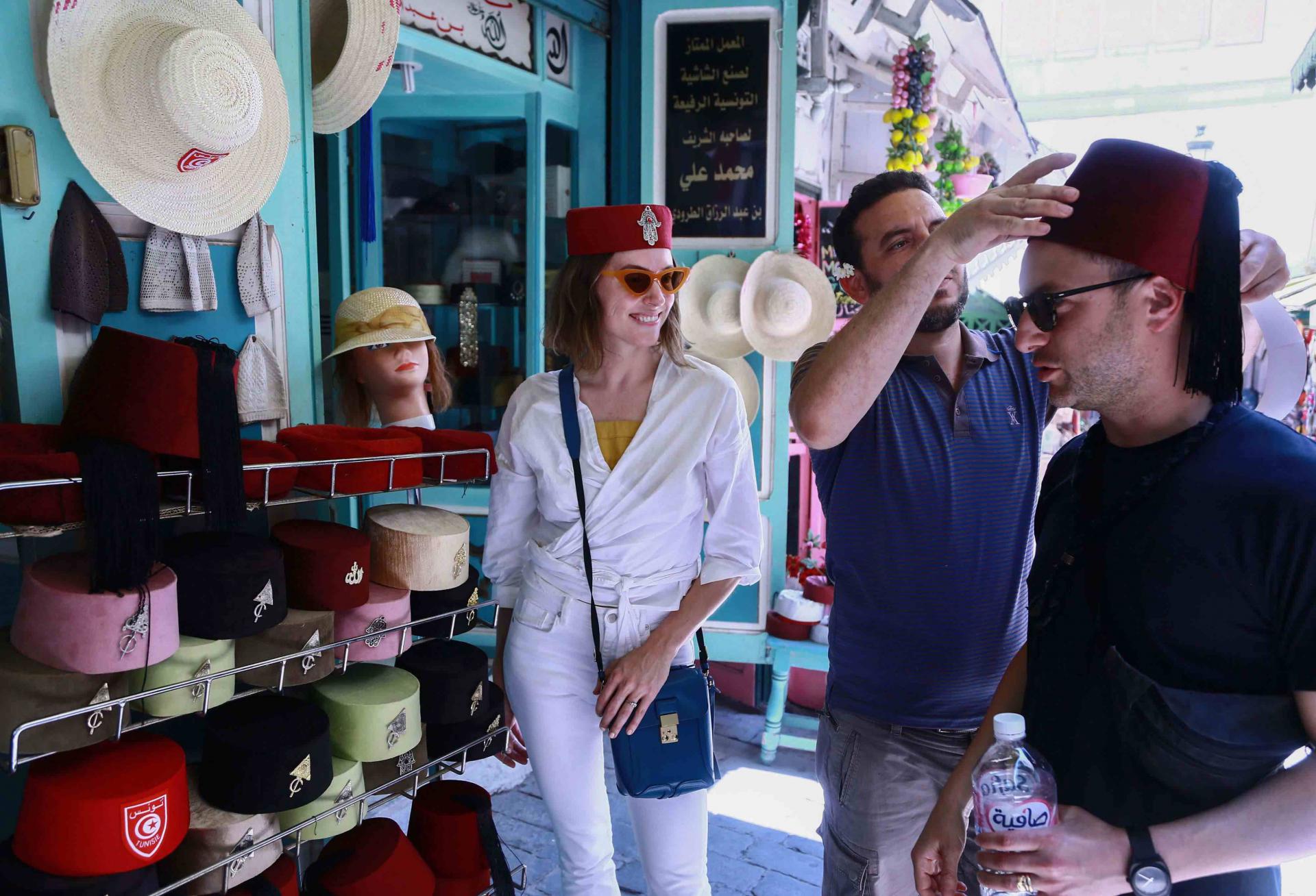 A tourist tries on a Tunisian “chechia” (traditional fez) in a shop at a bazaar in the Medina (old town) of Tunis