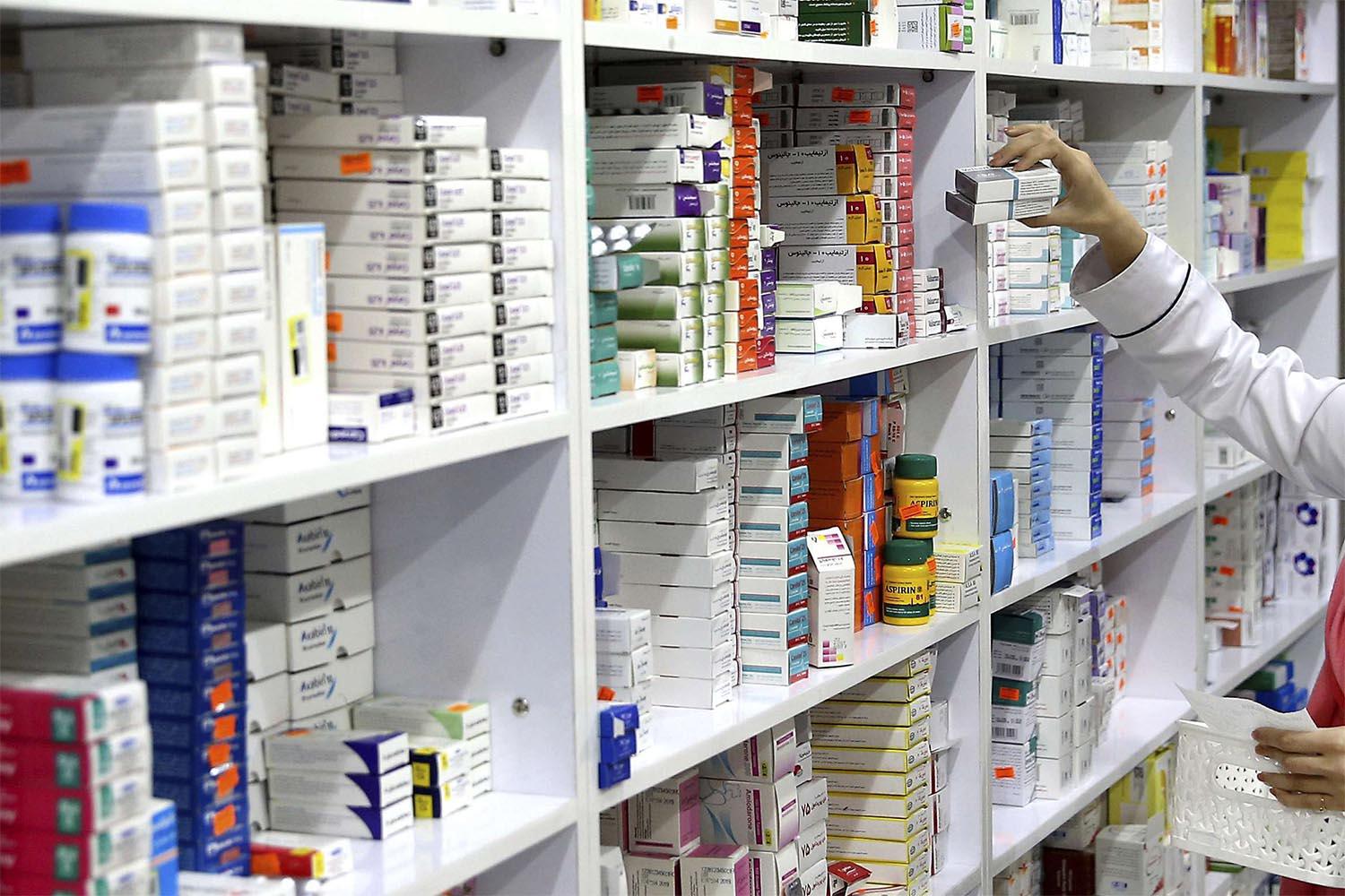 A drugstore employee reaches for medicine from shelf in Tehran