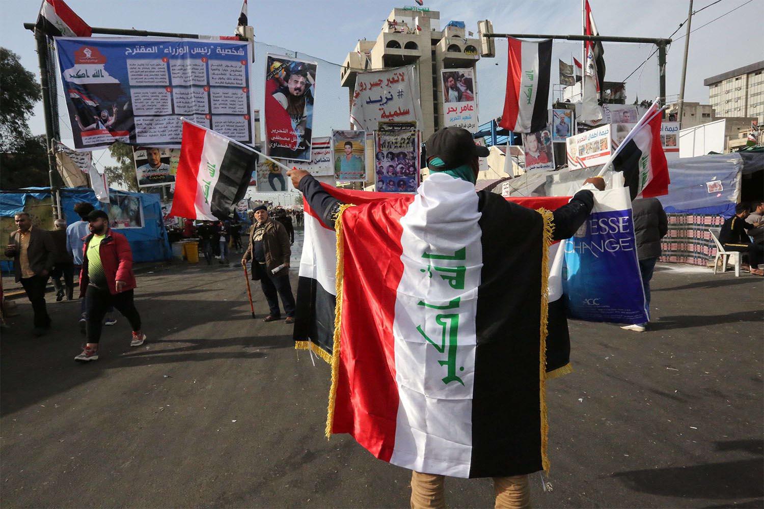 An Iraqi protester clad with the national flag takes part in anti-government protests at Tahrir square in Baghdad
