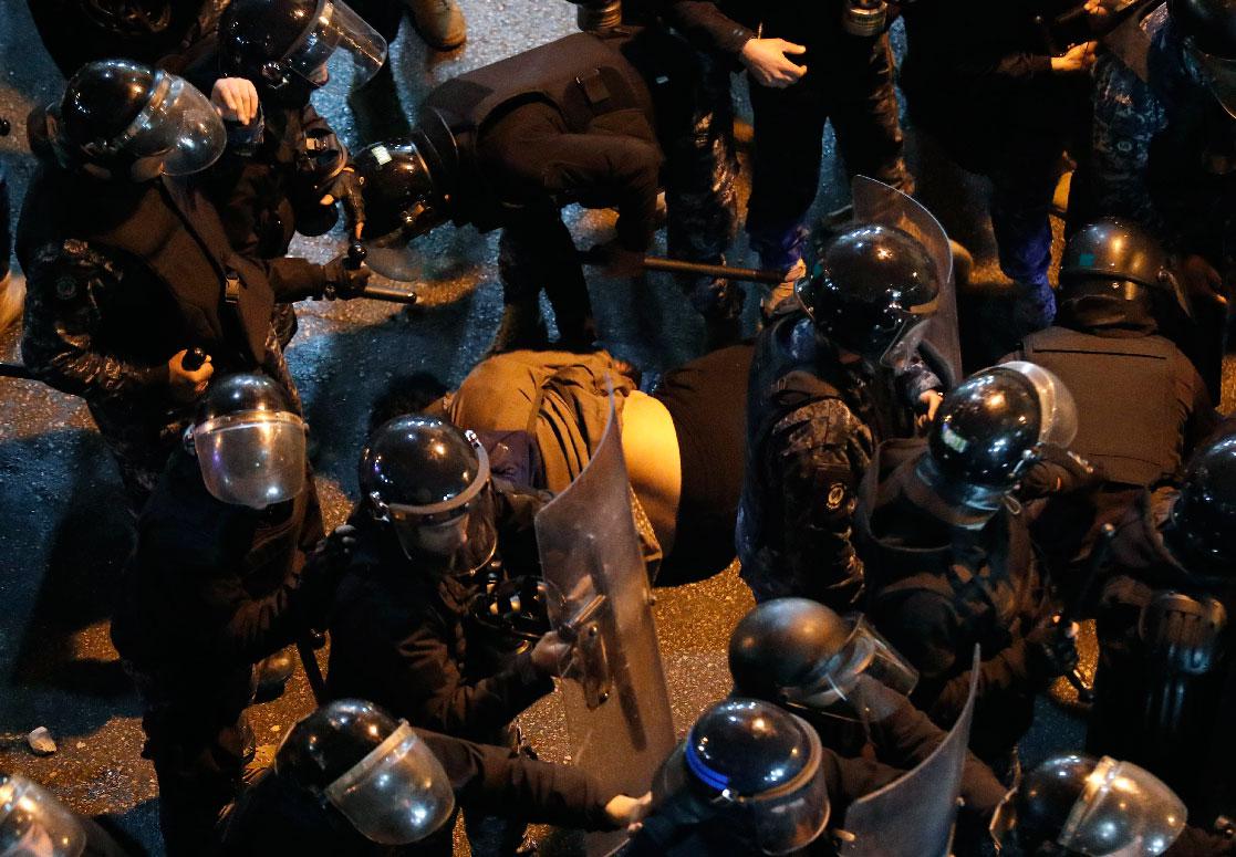 Riot police check a fainting anti-government protester during a demonstration to demand the release of detainees