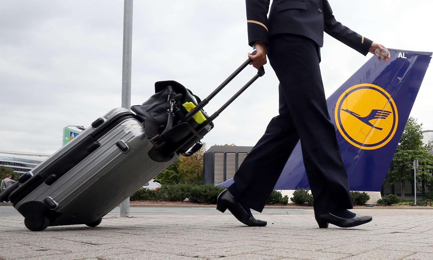 A flight attendant pulls his suitcase prior to a flight at the Lufthansa base of the Frankfurt airport