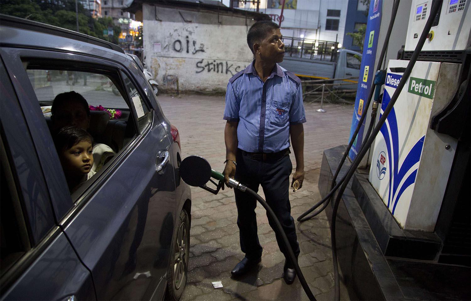 Indians get fuel filled in their car at a petrol pump in Gauhati, India