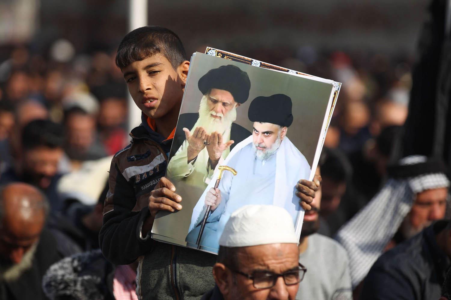 طفل عراقي يرفع صورة مقتدى الصدر وأبيه الراحل محمد صادق الصدر