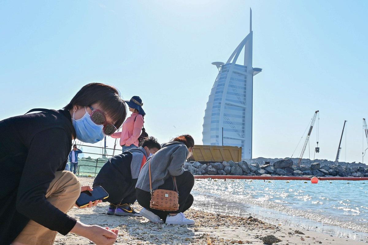 سياح يلبسون كمامات واقية عند شط برج العرب في دبي
