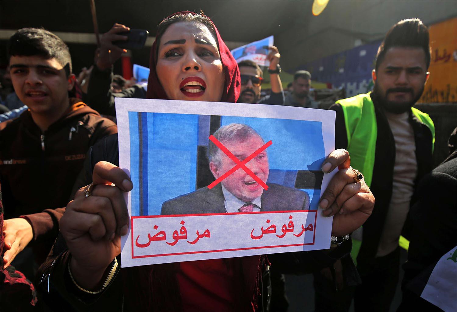 n Iraqi protester lifts pictures of the premier-designate Mohammad Allawi with the inscription "rejected"
