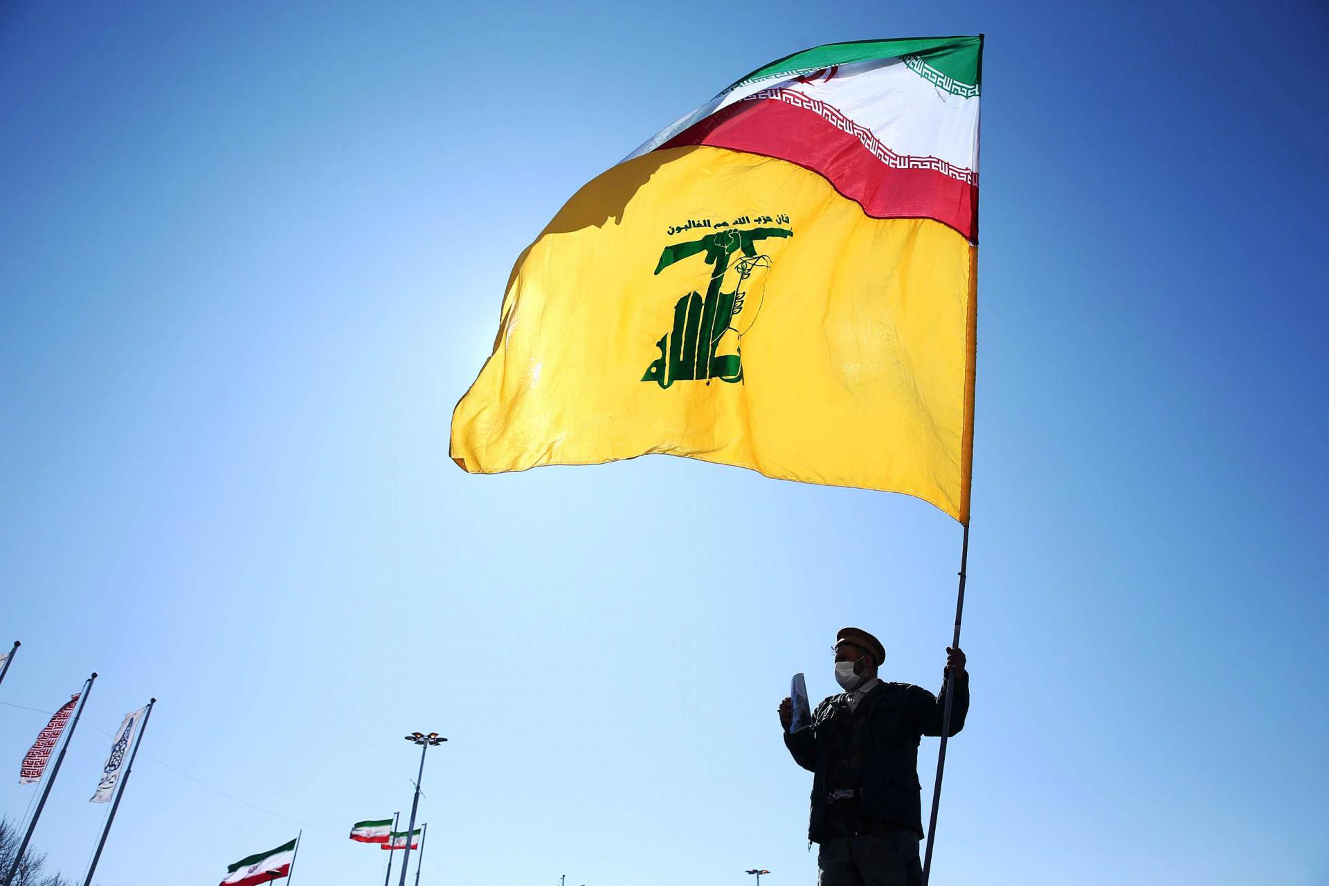 راية حزب الله اللبناني مع العلم الايراني يرفعها احد عناصره