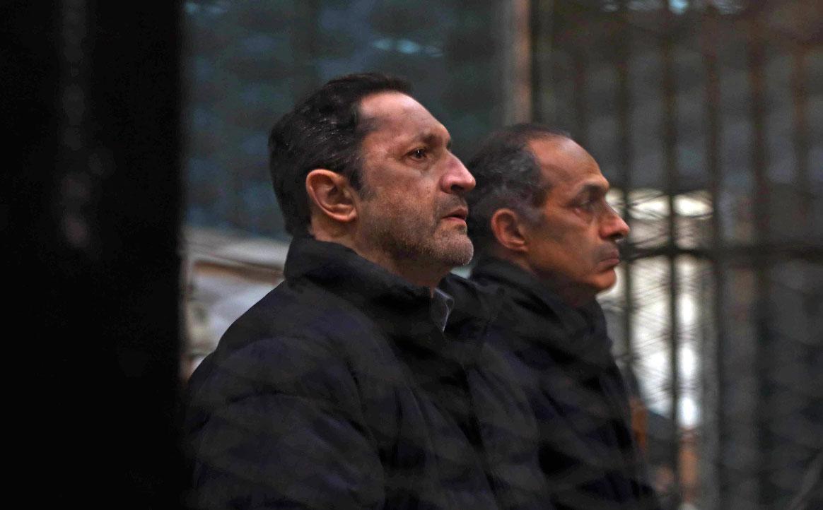 Alaa and Gamal Mubarak, sons of former Egyptian president Hosni Mubarak, sit inside the defendants' cage at the Police Academy courthouse in Cairo