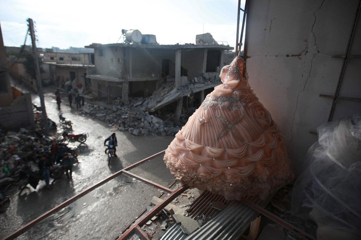 A wedding dress is seen in the destroyed window of a bridal shop in a damaged building in Balyun in Syria's Idlib province
