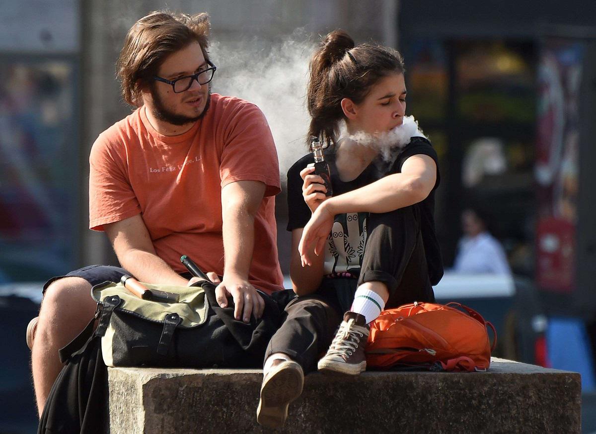 فتاة تدخن سيجارة الكترونية بالقرب من صديقها