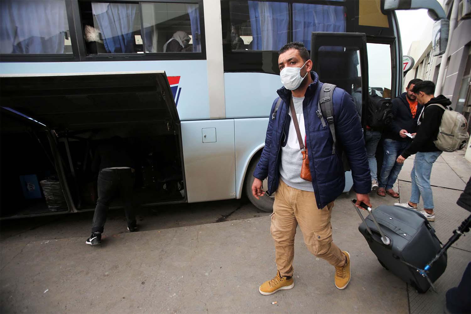 A man wearing a protective face mask walks with luggage, following the outbreak of coronavirus disease in Algiers