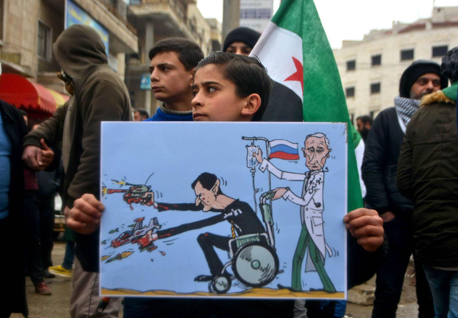 طفل سوري يحمل لوحة تسخر من الدعم الروسي للنظام السوري