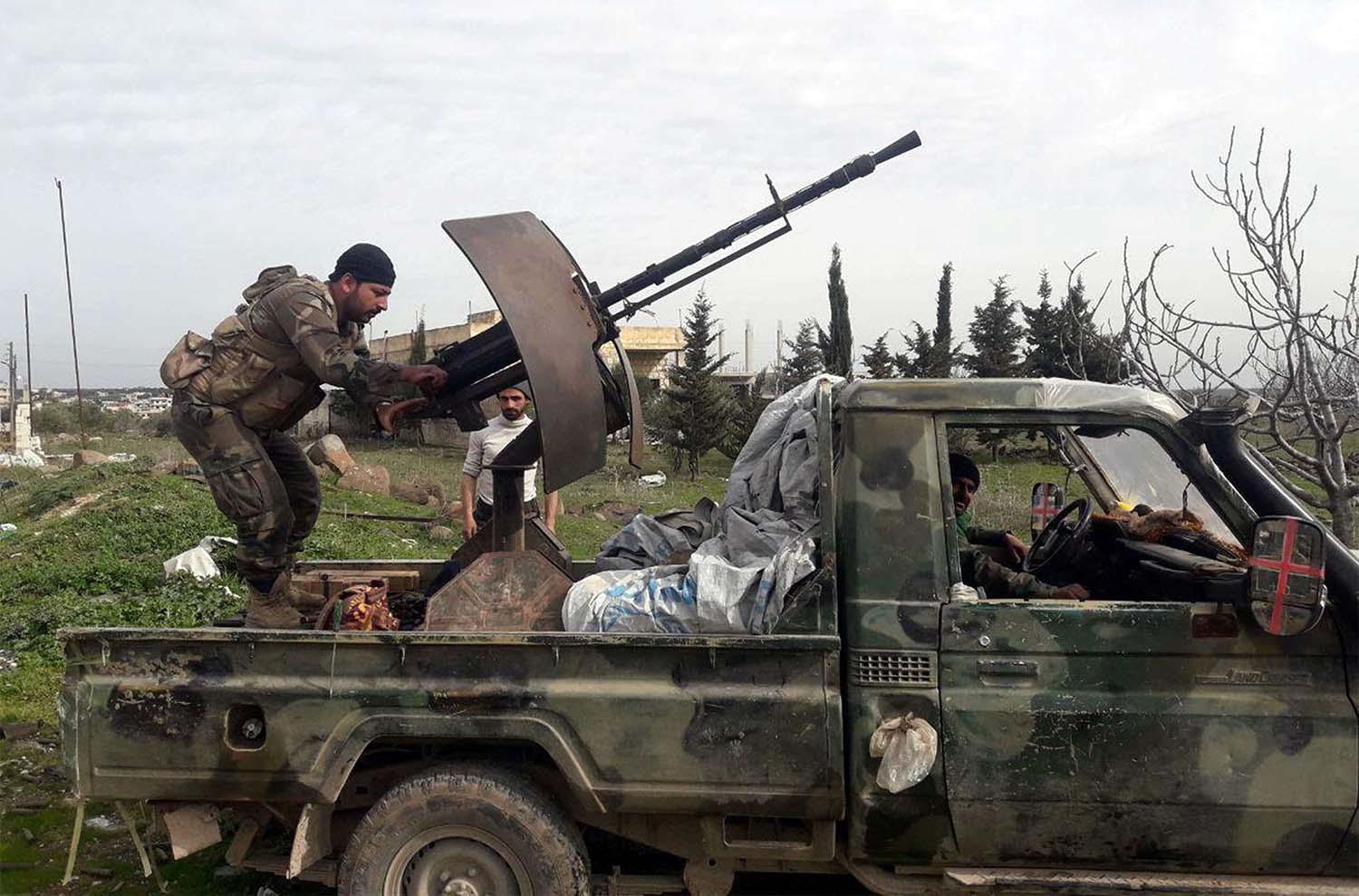 Syrian army soldiers gesture from a military vehicle in southern Idlib province