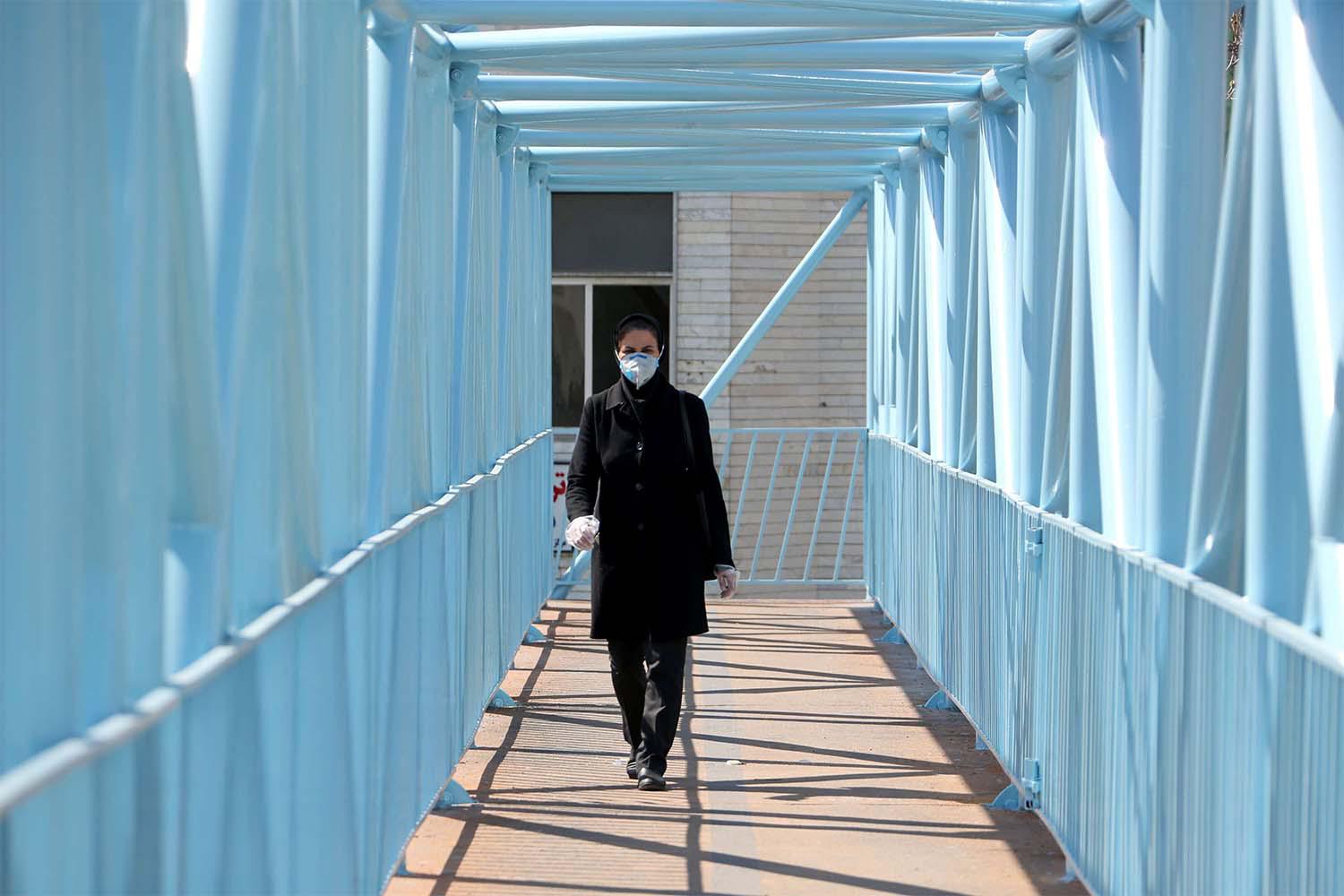 An Iranian pedestrian walks while wearing a protective mask in Tehran