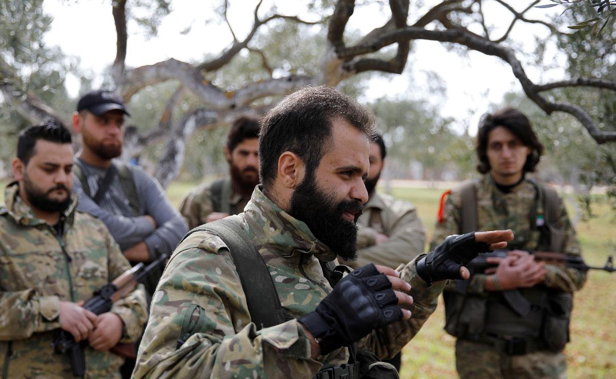 Ahmed Mansour gestures as he is with his comrades near Binnish, Syria