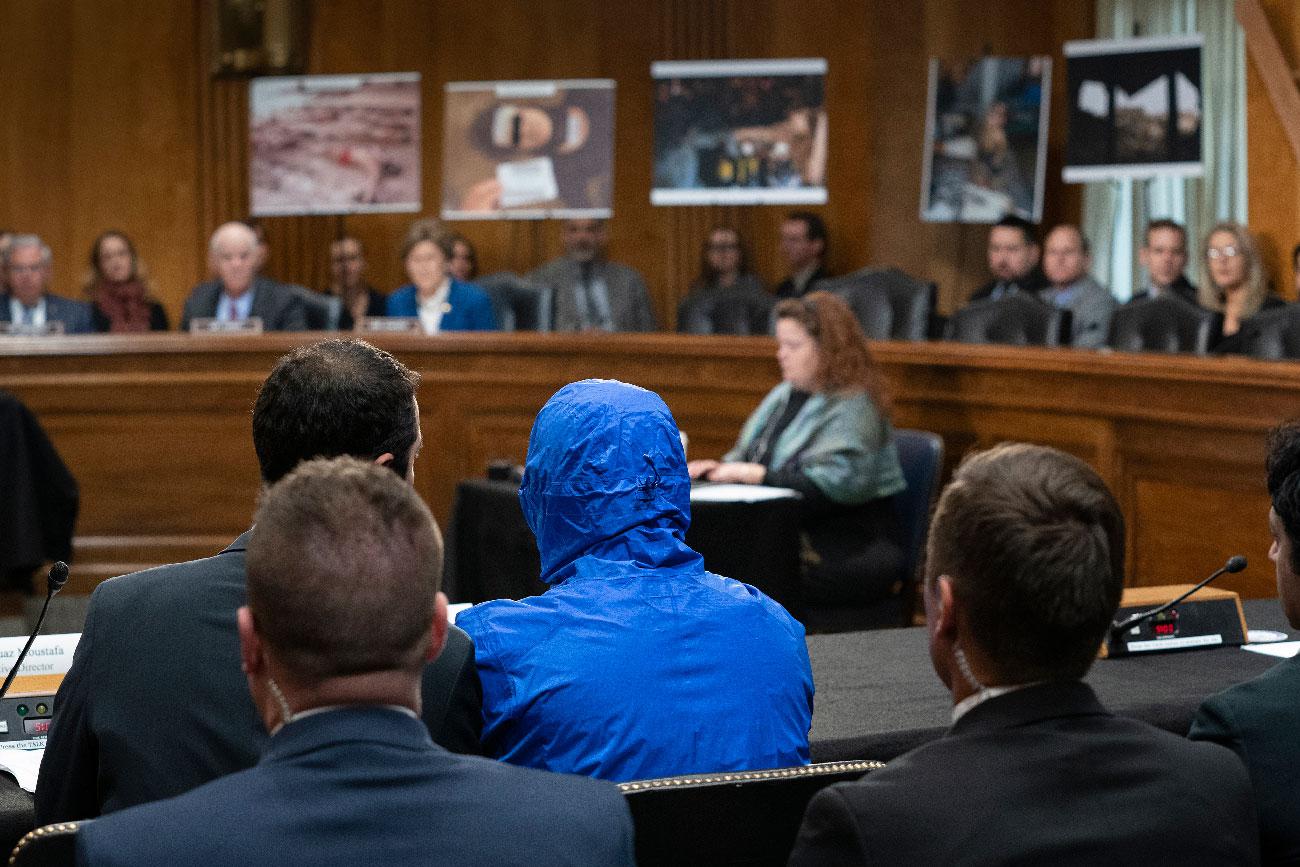 A Syrian military defector using the pseudonym 'Caesar' wears a hood as he testifies before the Senate Foreign Relations Committee