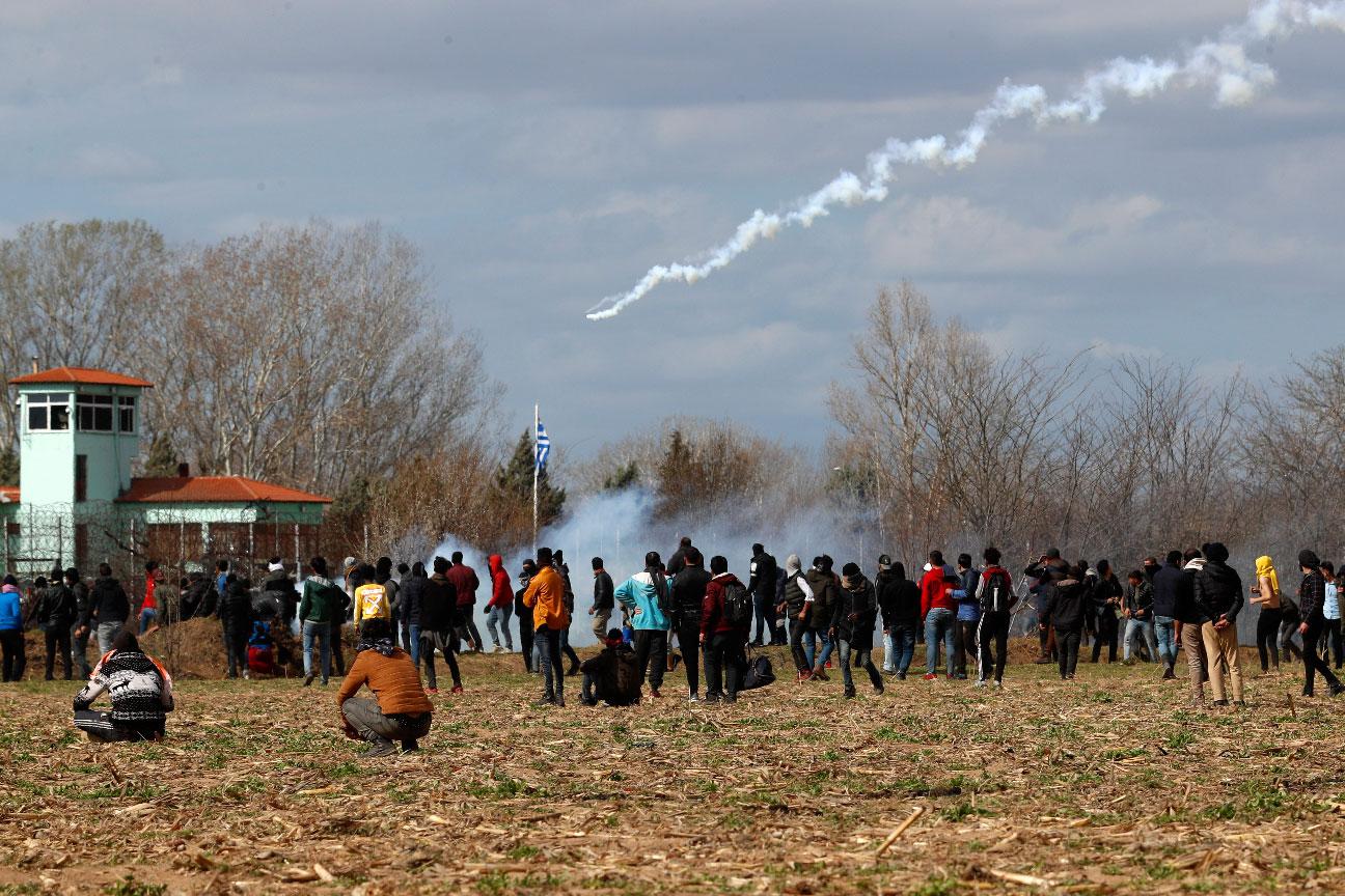 Migrants gather at a border fence on the Turkish side during clashes with the Greek riot police at the Turkish-Greek border in Pazarkule, Edirne region