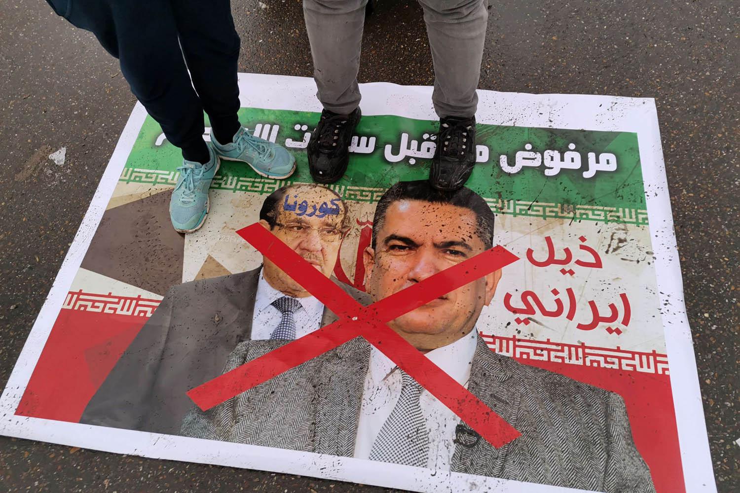 متظاهرون يدوسون على ملصقات لرئيس الوزراء المكلف عدنان الزرفي ورئيس الوزراء الأسبق نوري المالكي