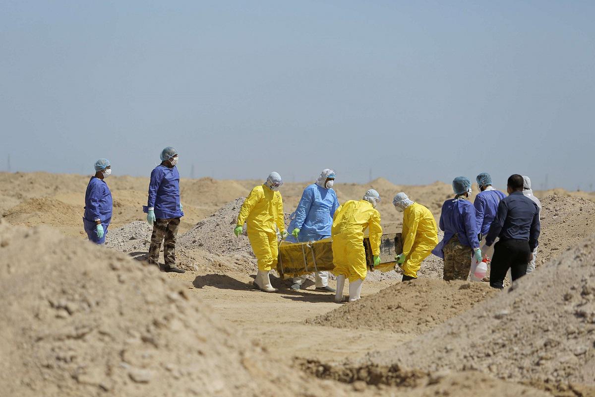 عمال وزارة الصحة العراقية يحملون تابوت شخص مات من فيروس كورونا 
