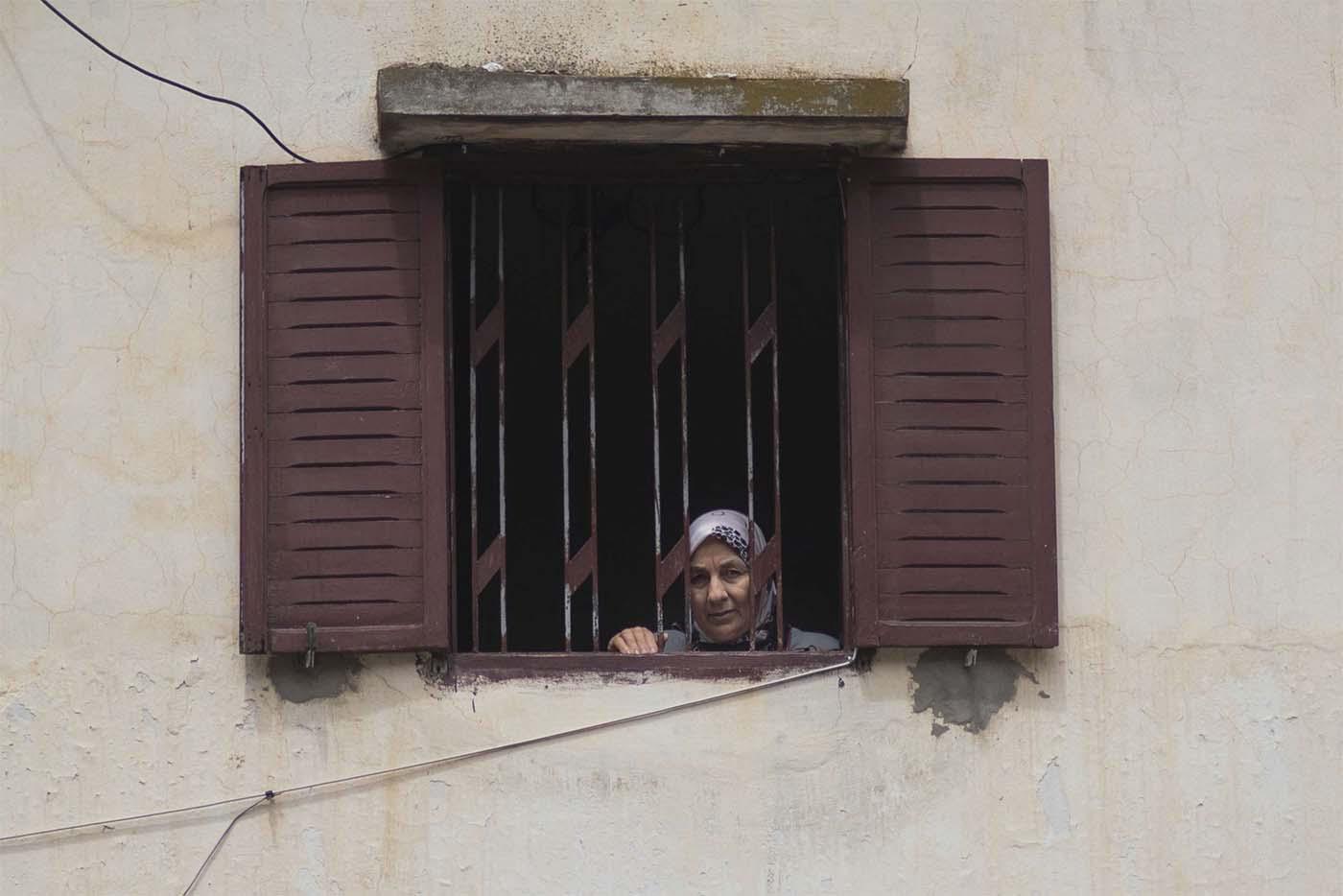 A woman looks out of her window during a health state of emergency and home confinement order in Rabat