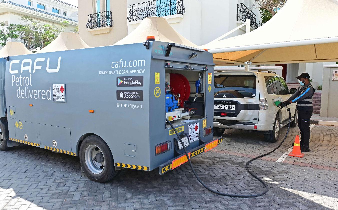 Ugandan Mullika Indy, an employee of CAFU, refills a client's car from a mini tanker 