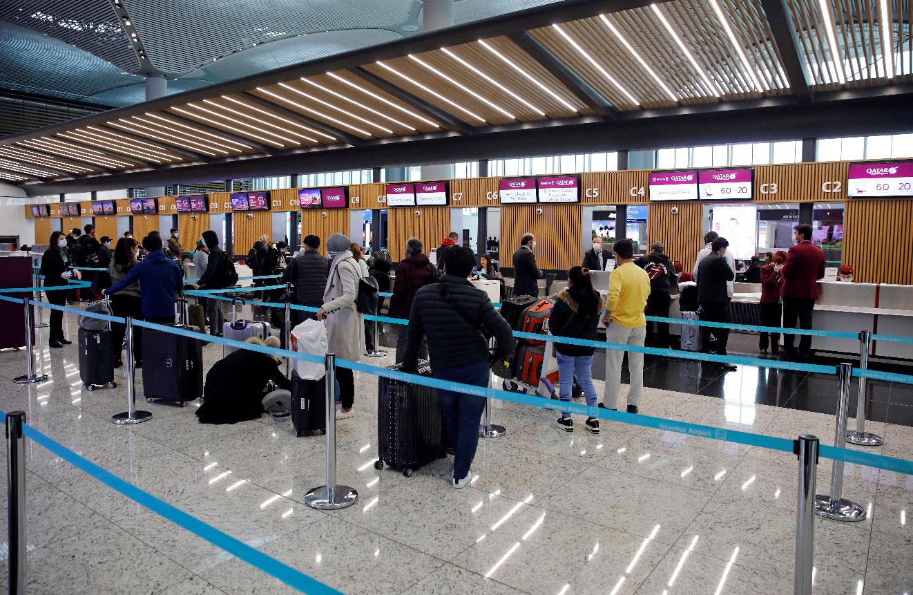 Passengers wearing protective face masks queue for a check-in, during the outbreak of the coronavirus disease (COVID-19), at Istanbul Airport