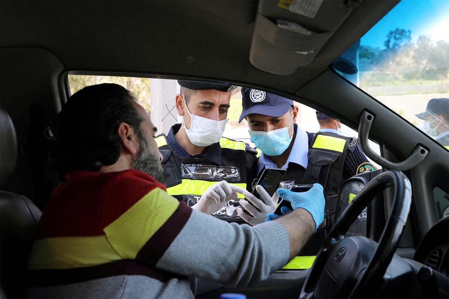 Jordanian policemen check the electronic pass of a driver in Amman