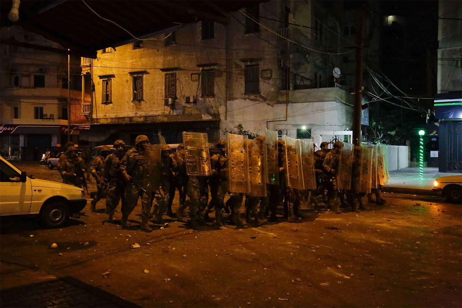 Lebanese army soldiers advance as protesters throw stones amid overnight confrontations in Tripoli