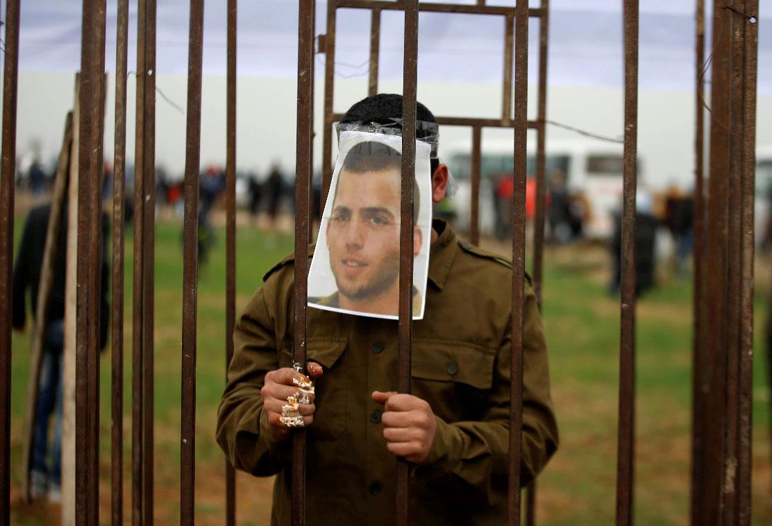 A Palestinian man playing the role of Israeli soldier Oron Shaul stands in a mock jail during a rally in solidarity with Palestinian prisoners