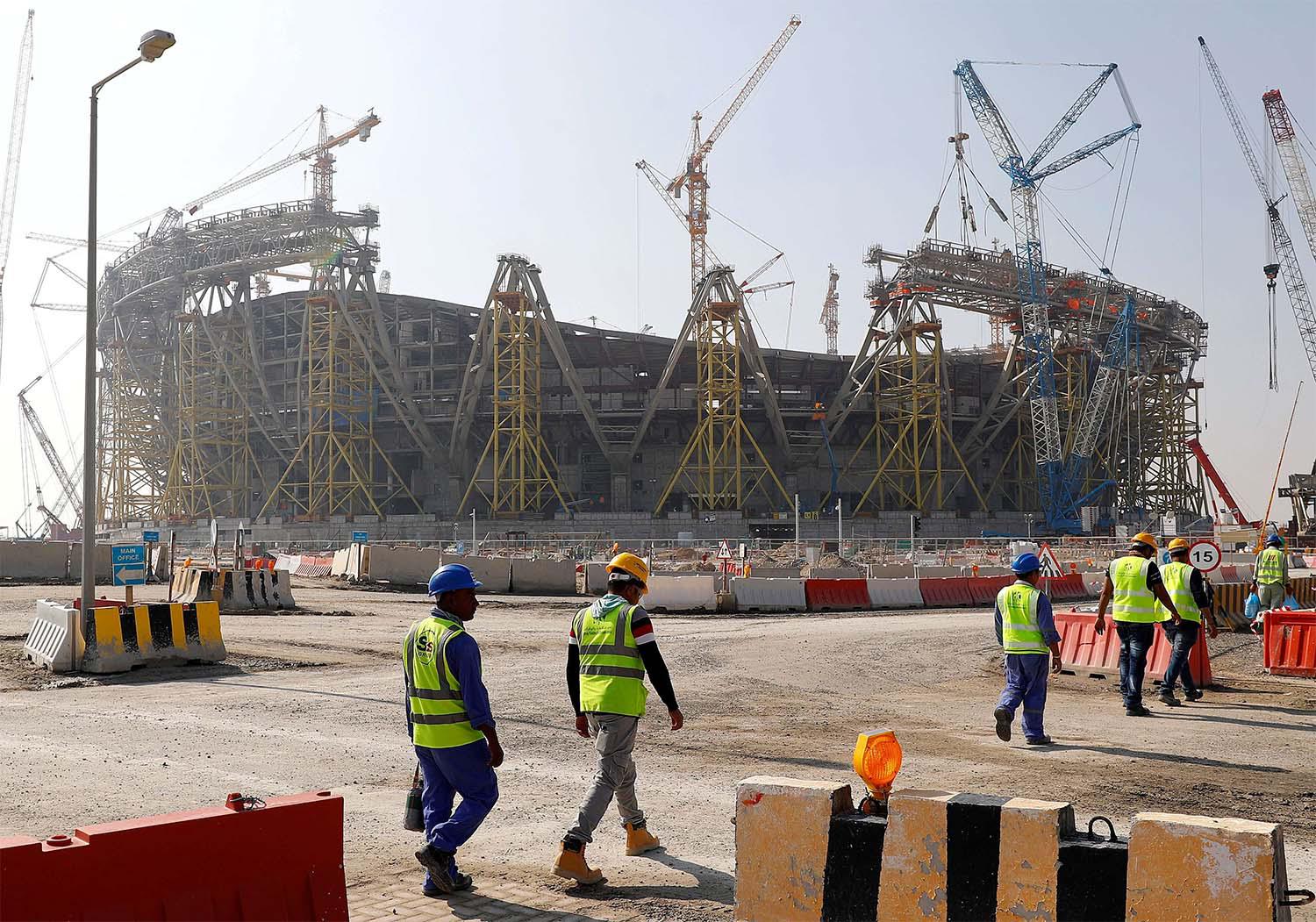 Workers walk towards the construction site of the Lusail stadium in Doha