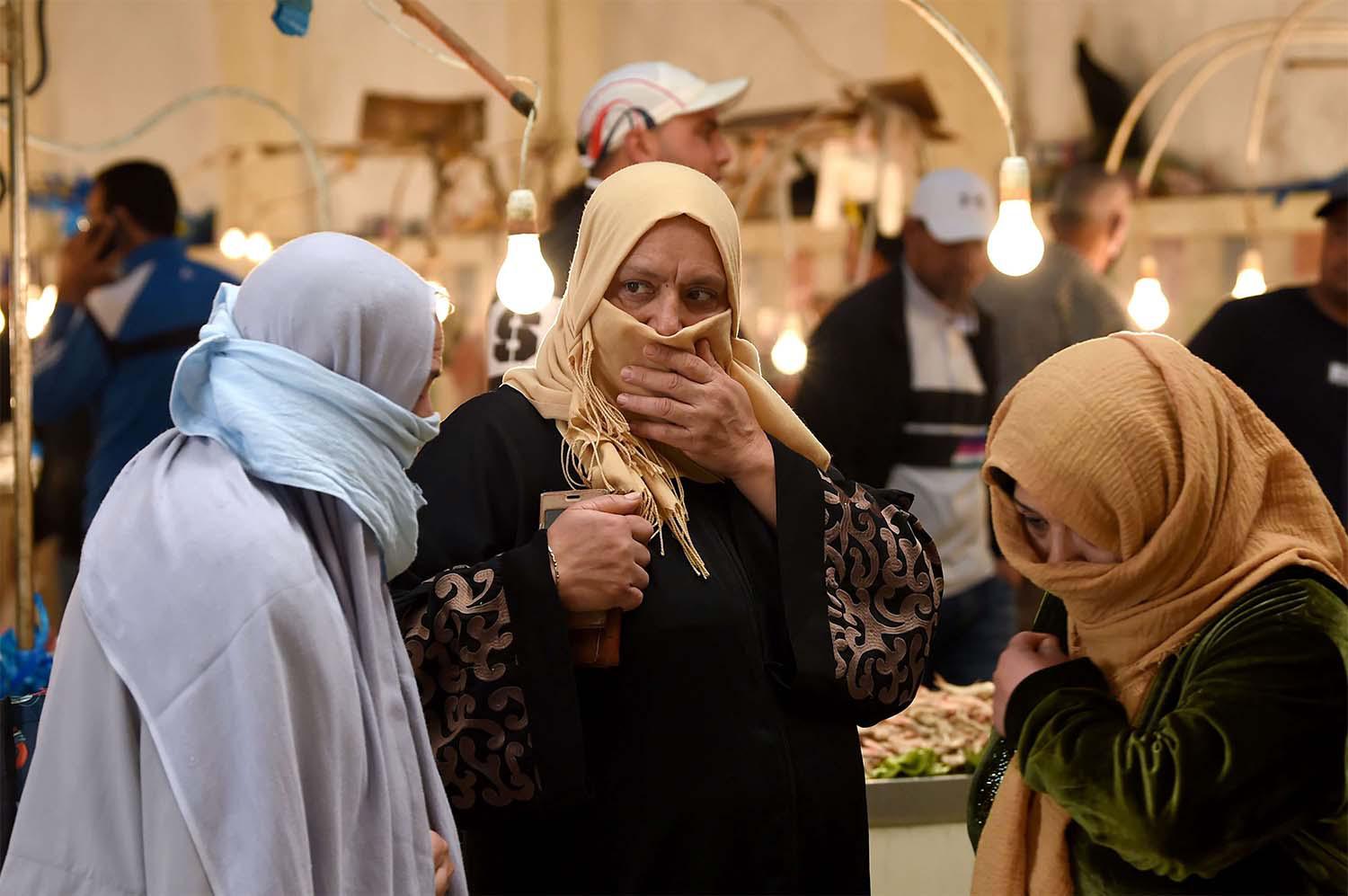Tunisian women, covering their faces, walk past stalls in a central market in the capital Tunis