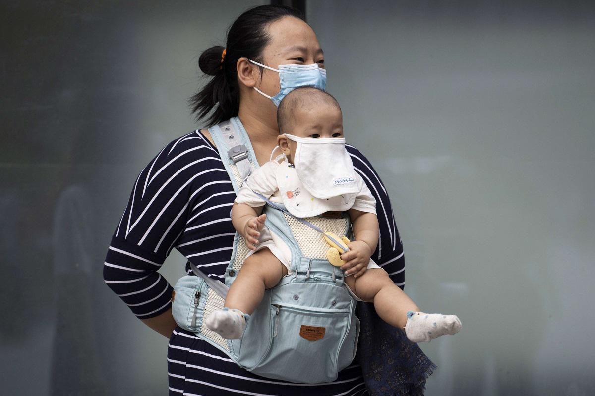 أم صينية تضع وطفلها كمامتين للوقاية من فيروس كورونا