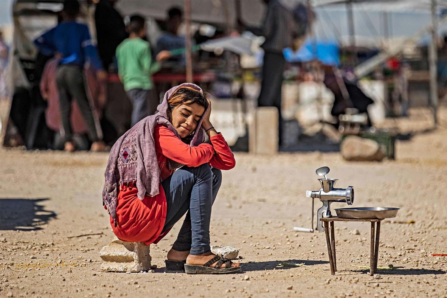A displaced Syrian girl sits at the Washukanni camp