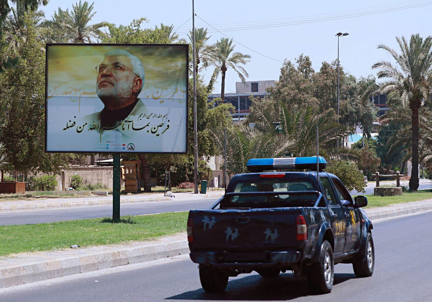دورية أمنية عراقية وسط بغداد تمر بجانب صورة لأبو مهدي المهندس