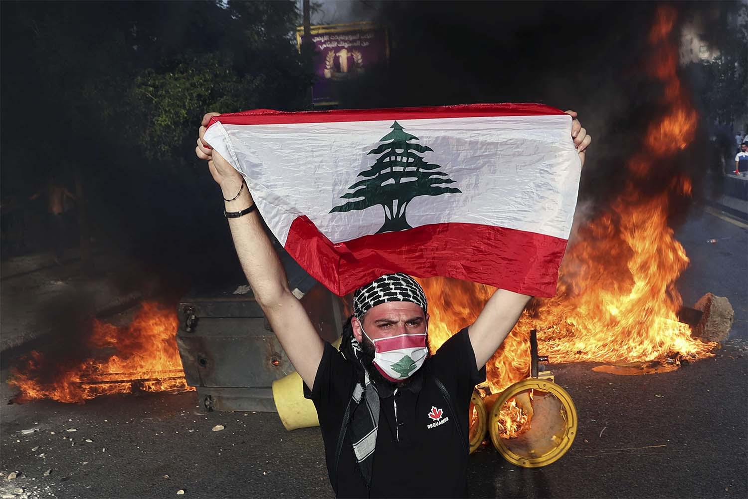 An anti-government protester holds up a Lebanese flag