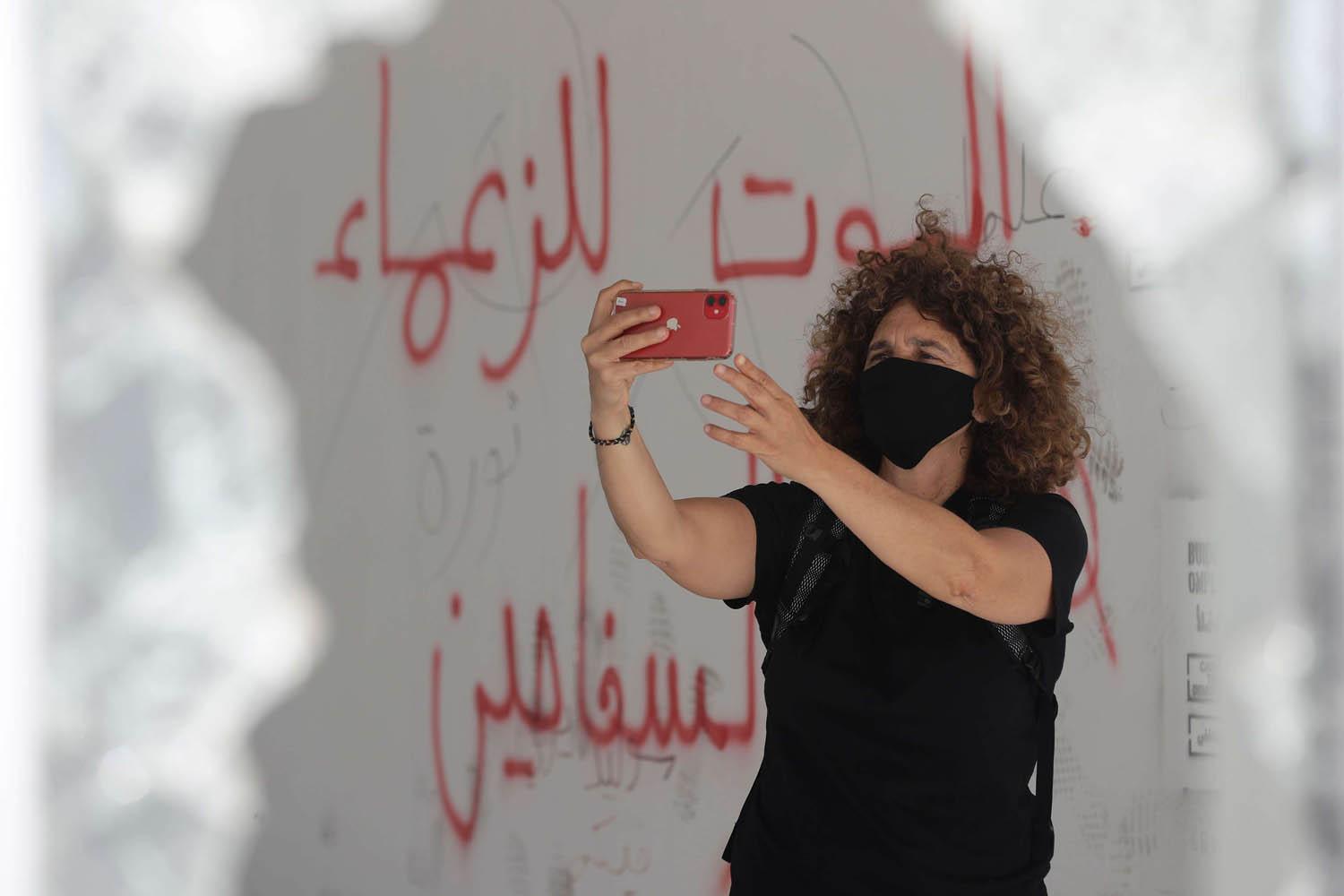 المخرجة اللبنانية كارول منصور في سيلفي مع شعارات على الحائط في بيروت
